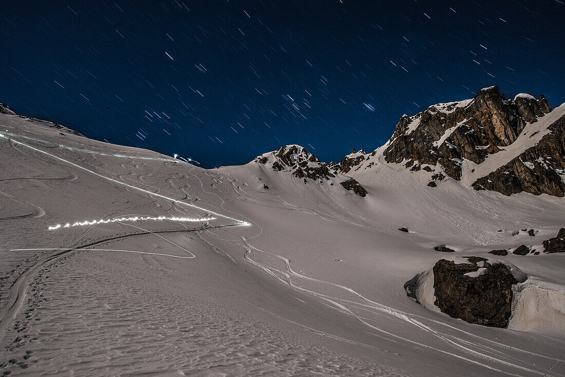 Skitourengeher bei Vollmond (Aufstiegs- und Abfahrtsspur) bei Grialetschhütte, Graubünden, Schweiz, Europa