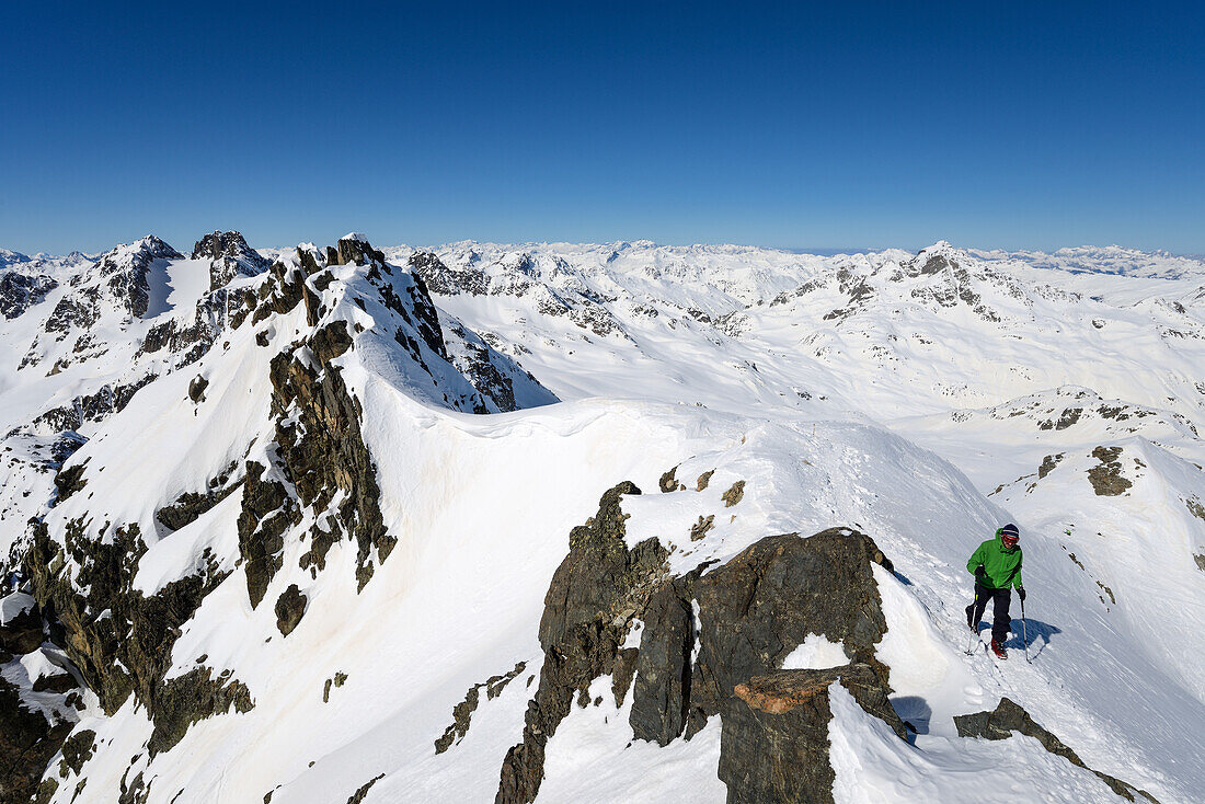 A mountaineer close to the summit of Piz Sarsura (3178 m), in the background Grialetschhut with Piz Radoent and Schwarzhorn, summits on the horizon (from left to right): Piz Vadret, Titlis, Toedi, Clariden, Buendner Vorab, Ringelspitz, Pizol, Hochfinsler,