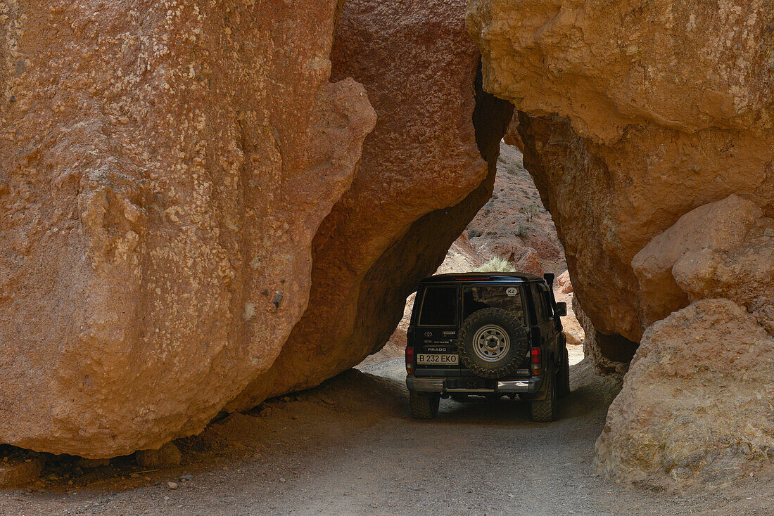 Jeep fährt durch Felsspalte im Scharyn Canyon, Scharyn Nationalpark, Region Almaty, Kasachstan, Zentralasien, Asien