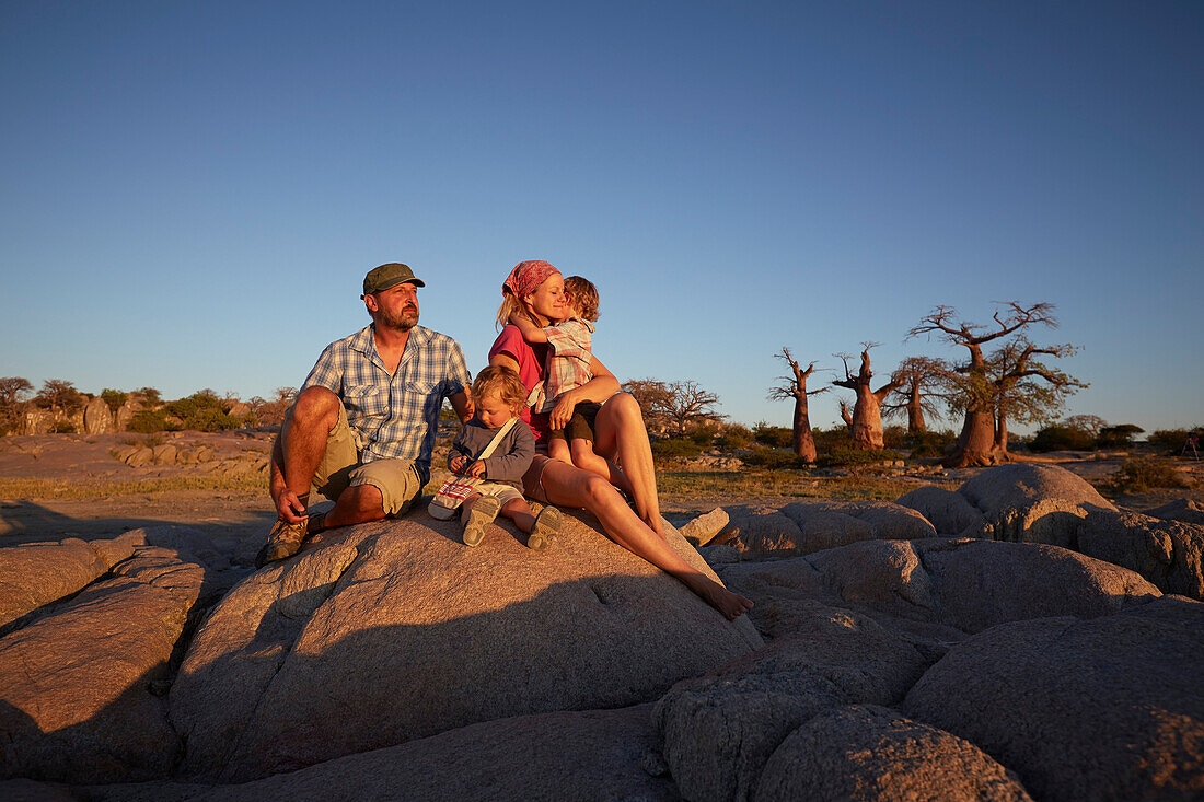 Family sitting on a rock at sunset, Kubu Island, Makgadikgadi Pans National Park, Botswana
