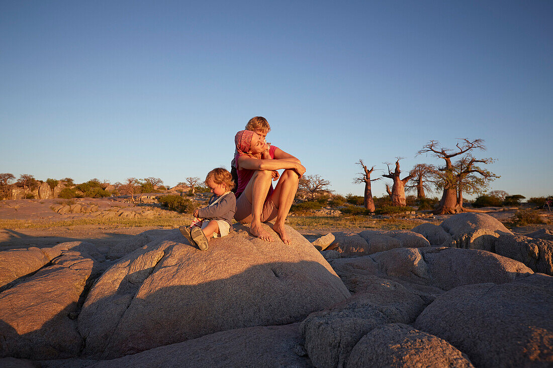 Mutter und Söhne auf einem Felsen im Sonnenuntergang, Kubu Island, Makgadikgadi Pans Nationalpark, Botswana