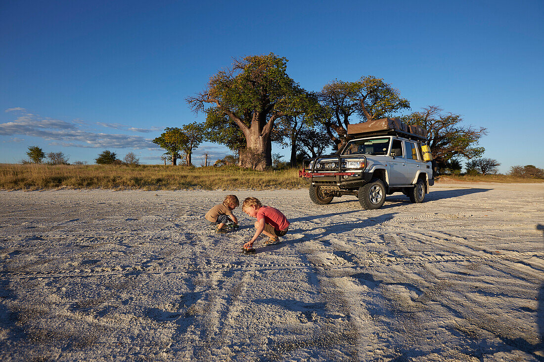 Boys playing in sand at sunset, Tutume, Nxai Pan National Park, Botswana