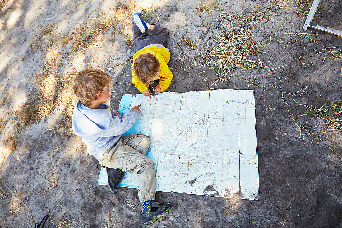 Zwei Jungen schauen sich eine Landkarte an, Makgadikgadi-Pans-Nationalpark, Botswana