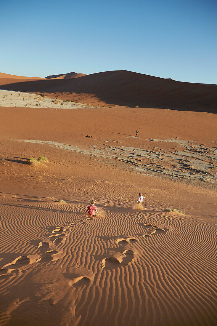 Zwei Jungen rennen Sanddüne hinunter, Deadvlei, Sossusvlei, Namib-Naukluft-Nationalpark, Namibia