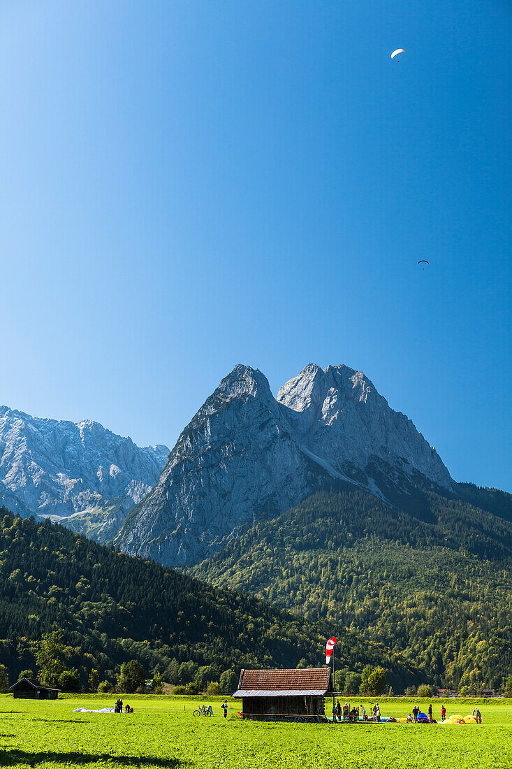 Paragliders above Waxenstein and landing site, Garmisch-Partenkirchen, Bavaria, Germany