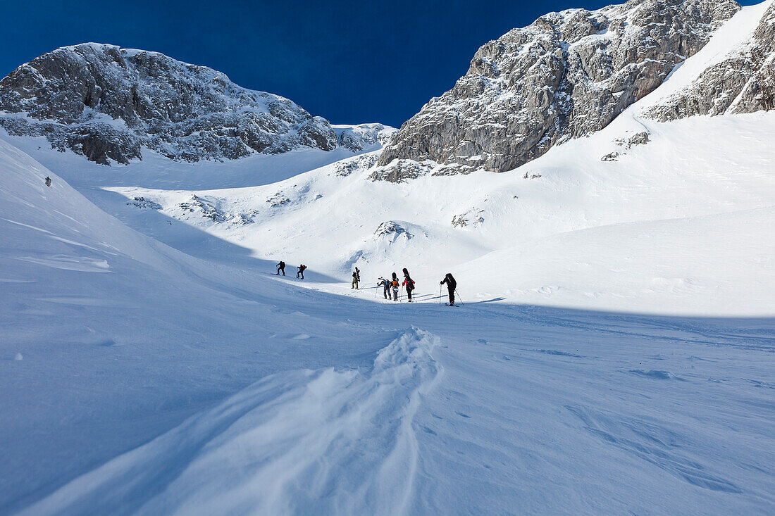 Backcountry skiers and snowboaders ascending Sonntagskogel peak, Tennengebirge mountains, Salzburg, Austria