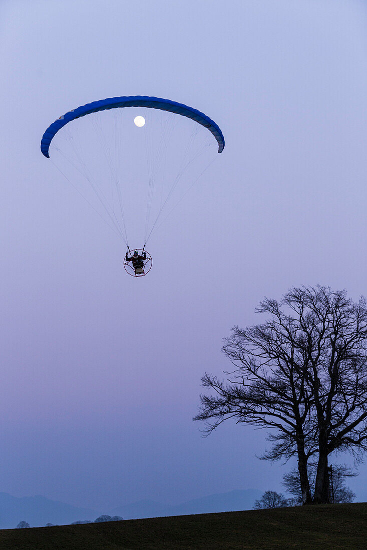 Motor-Gleitschirm und Mond in der Abenddämmerung, Penzberg, Oberbayern, Deutschland