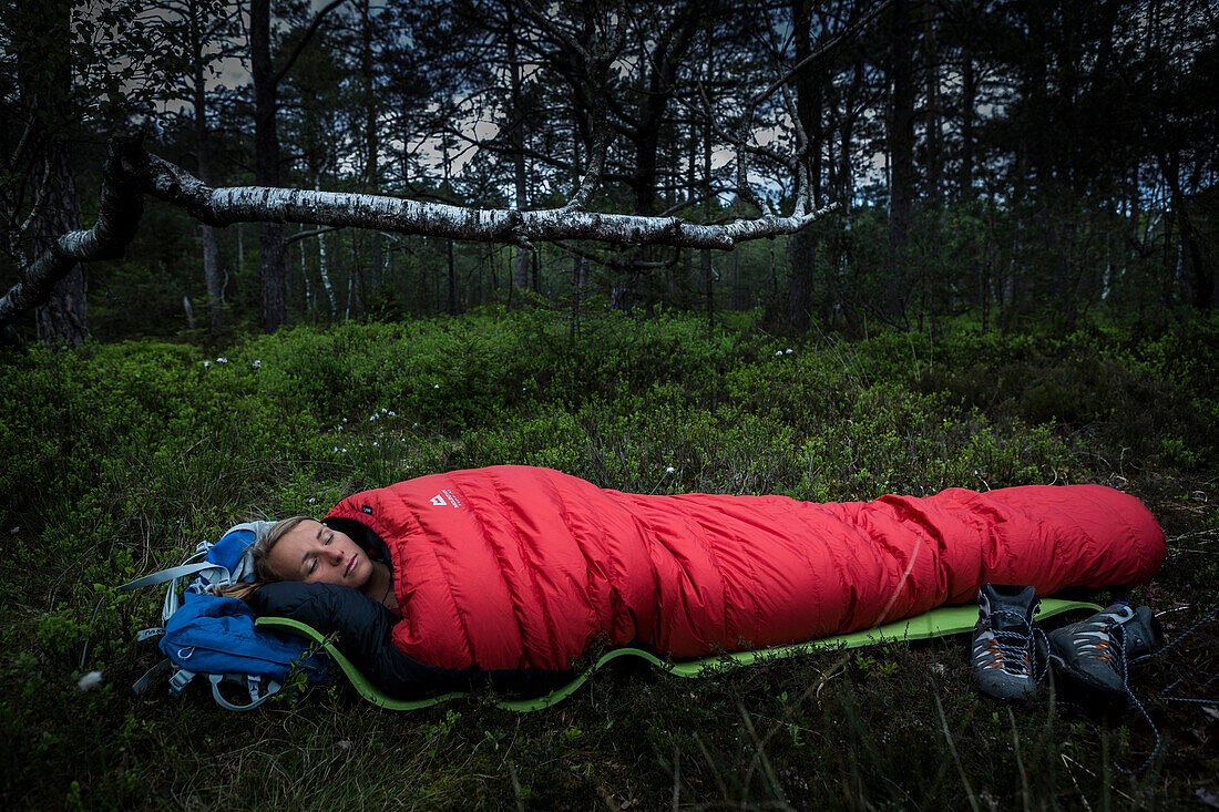 young woman in sleeping bag in a moorland forest, Berg at Lake Starnberg, Upper Bavaria, Germany