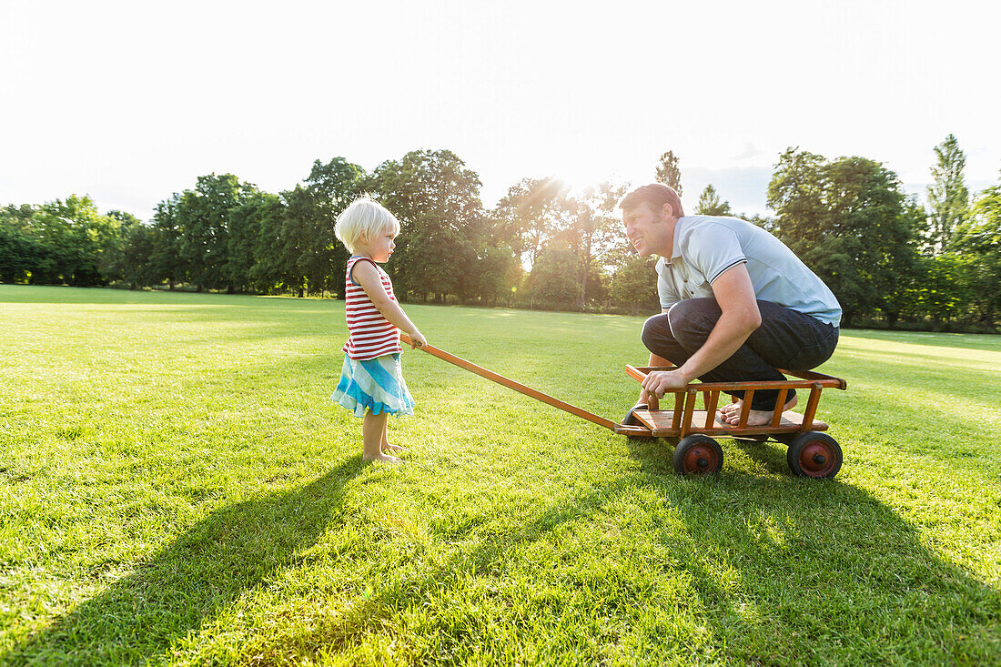 two-year-old girl pulling her father across the meadow, Speyer, Rheinland-Pfalz, Germany