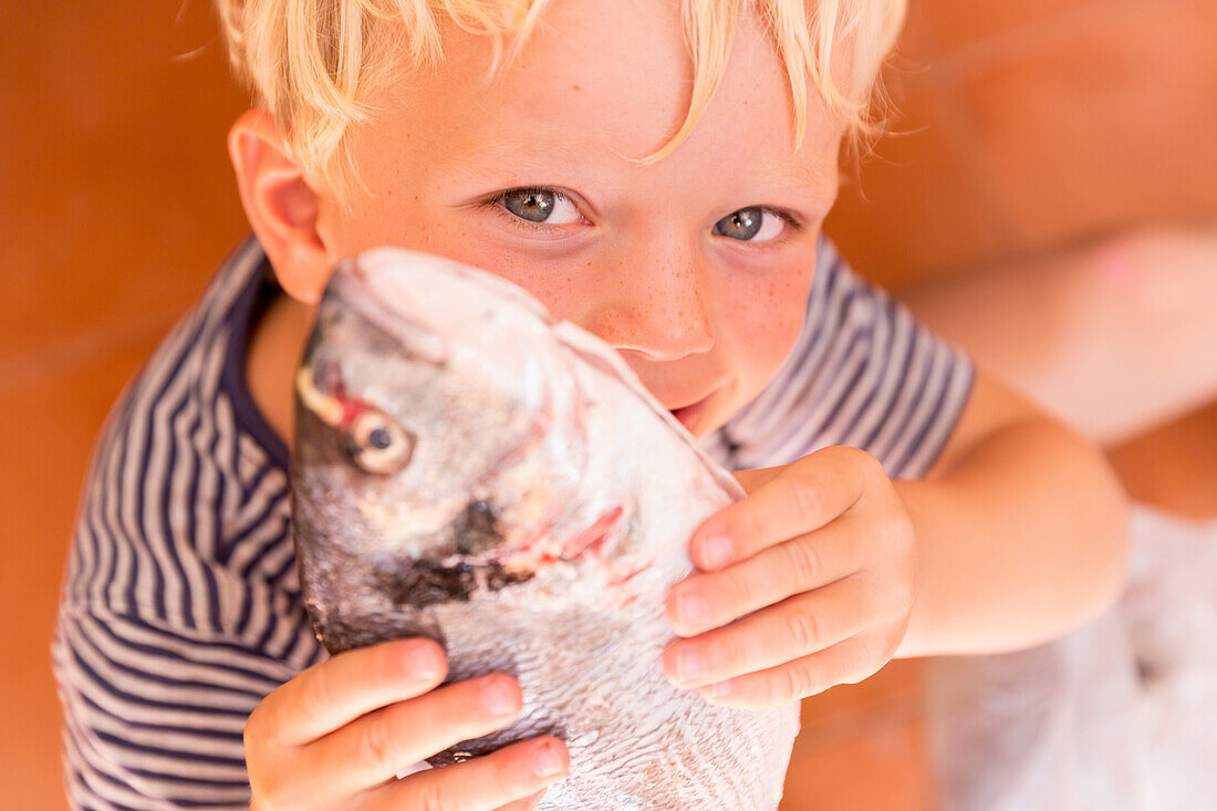 blonder Junge, 4 Jahre hält einen Fisch, frisch vom Fischmarkt, Dorade, MR, Soller, Serra de Tramuntana, Mallorca, Balearen, Spanien, Europa