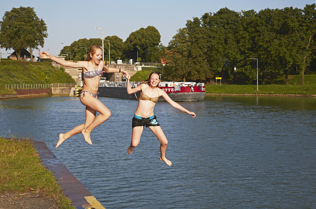 Two girls jump into the Dortmund-Ems-Kanal at lock Große Schleuse Bevergern ,  Muensterland , North Rhine-Westphalia , Germany , Europe