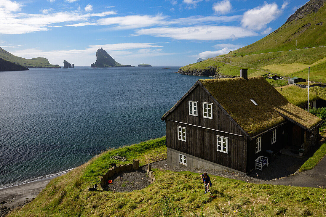 Traditionelles Haus mit Grasdach in Böur (Bøur), Insel Vagar. Im Hintergrund die Inseln Tindholmur und Drangarnir, Färöer Inseln (Føroyar)