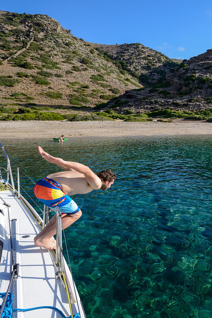 Man diving off a sailing yacht into a lonely bay of the greek island Kithnos, Kolona, Aegean, Cyclades, Greece
