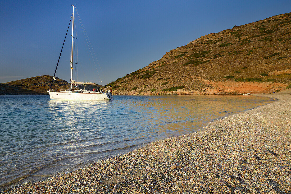 Sunrise above an anchoring sailing yacht in a lonely bay on the greek island Kithnos, Kolona, Aegean, Cyclades, Greece