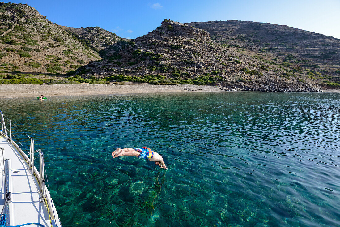 Man diving off a sailing yacht into a lonely bay off the greek island of Kithnos, Kolona, Aegean, Cyclades, Greece