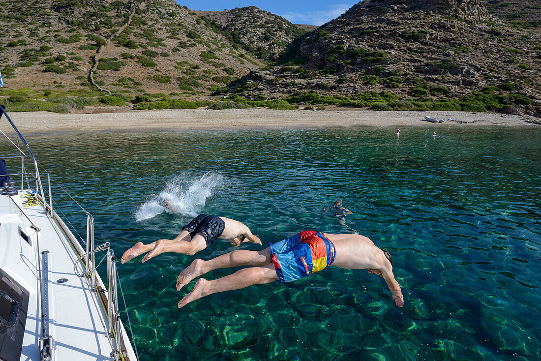 Junge Männer springen mit Köpfer von Segelyacht in einsame Bucht der griechische Insel Kithnos, Kolona, Ägäis, Kykladen, Griechenland