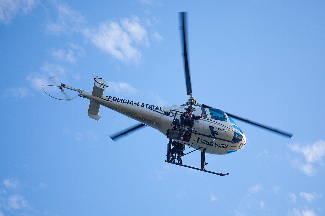Policial Estatal police helicopter above Playa Las Hamacas beach, Acapulco, Guerrero, Mexico
