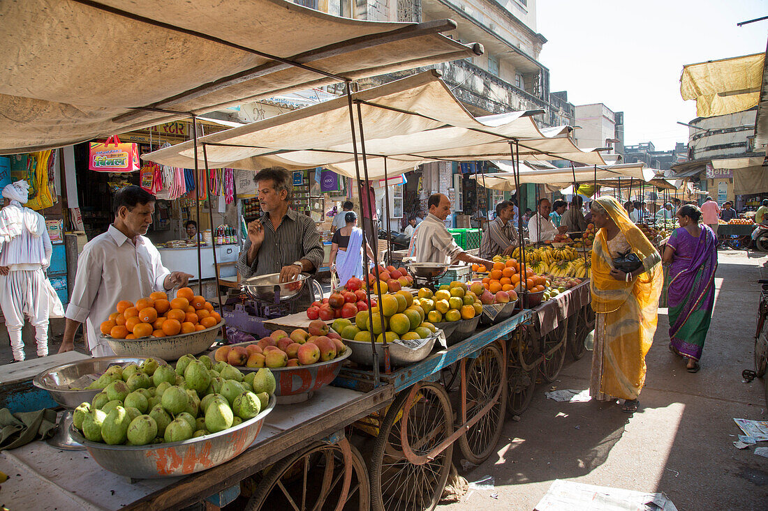 Menschen an einem Fruchtstand im Stadtzentrum, Porbandar, Gujarat, Indien