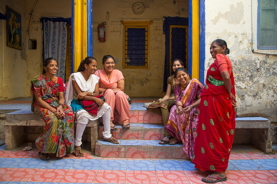 Frauen mit farbenfroher Kleidung vor einem alten Schulgebäude, Porbandar, Gujarat, Indien