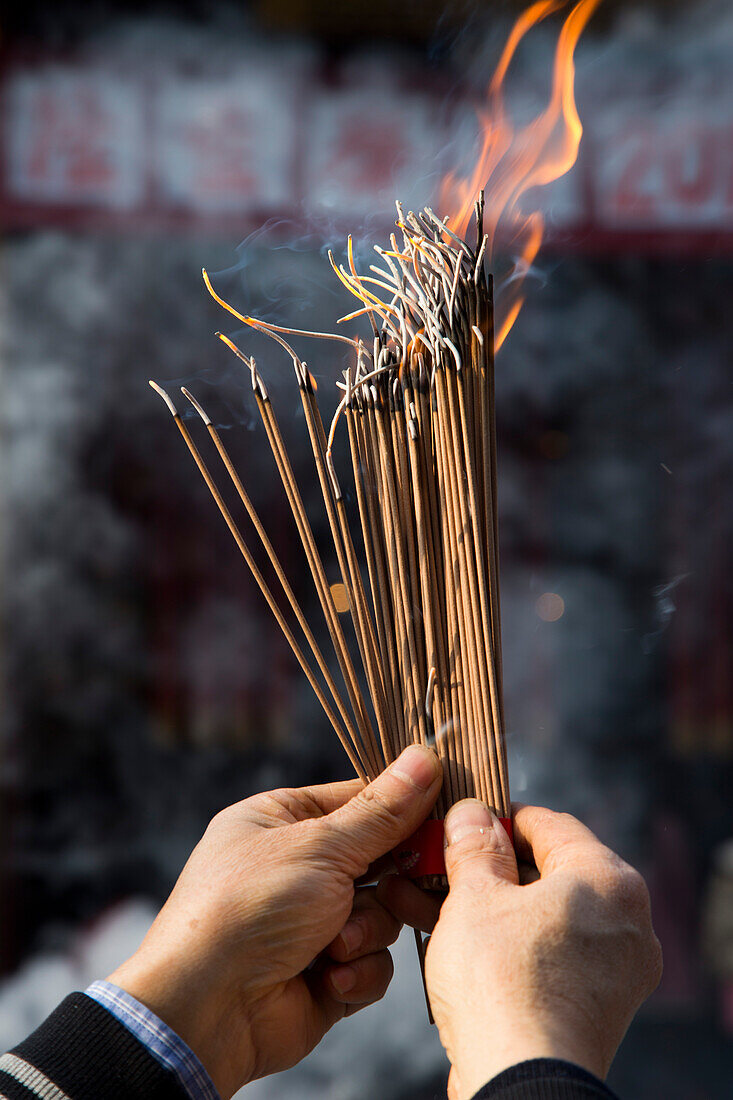 Hands hold incense during worship at Jade Buddha Temple, Shanghai, China
