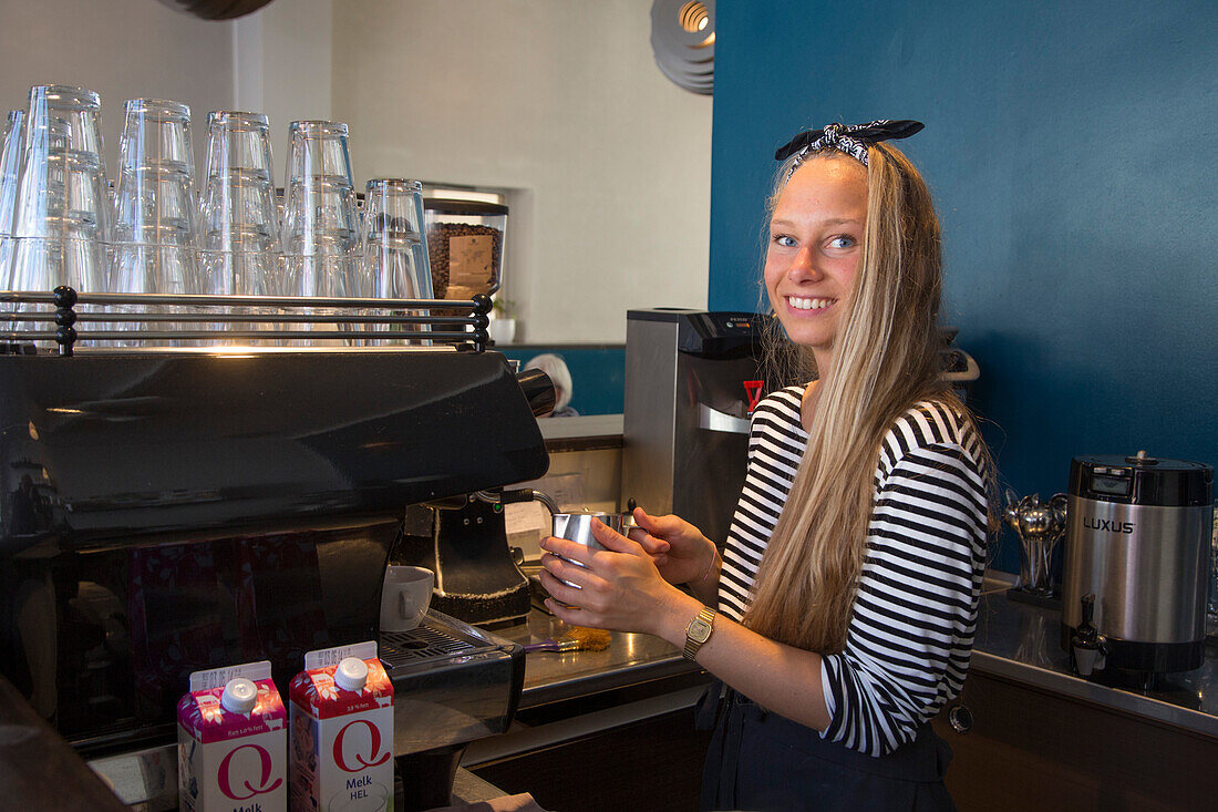 Hübsche junge Frau bereitet einen köstlichen Cappuccino im Café Kaffemisjonen zu, Bergen, Hordaland, Norwegen, Europa