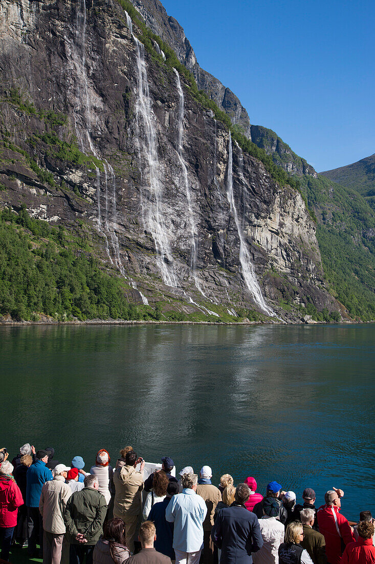 Passagiere an Deck von Kreuzfahrtschiff MS Deutschland (Reederei Peter Deilmann) blicken auf den Wasserfall Die Sieben Schwestern im Geirangerfjord, Geiranger, More og Romsdal, Norwegen, Europa