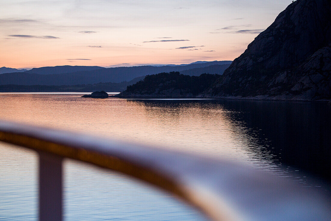 Railing of cruise ship MS Deutschland (Reederei Peter Deilmann) and fjord landscape at dusk, near Bergen, Hordaland, Norway