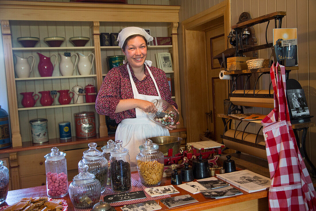 Fröhliche Frau in traditioneller Tracht im Süßwarengeschäft vom Sverresborg Trøndelag Freiluftmuseum, Trondheim, Sør-Trøndelag, Norwegen, Europa