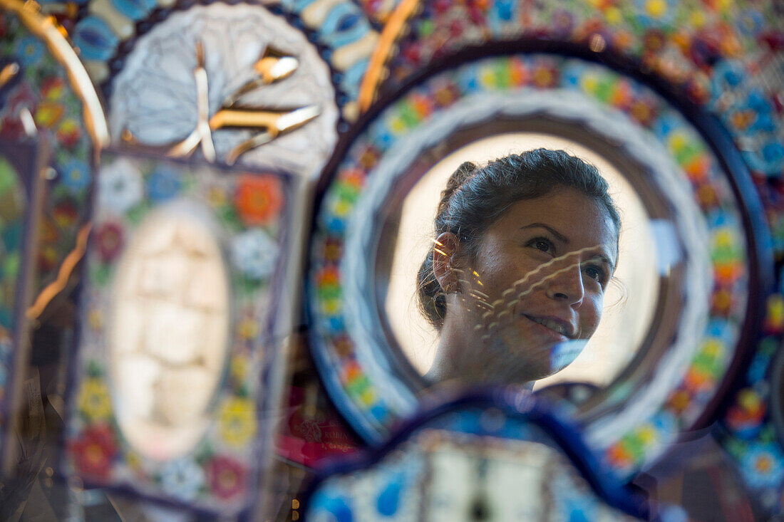 Reflection of young woman in ornamental glassware mirror, Seville, Andalusia, Spain