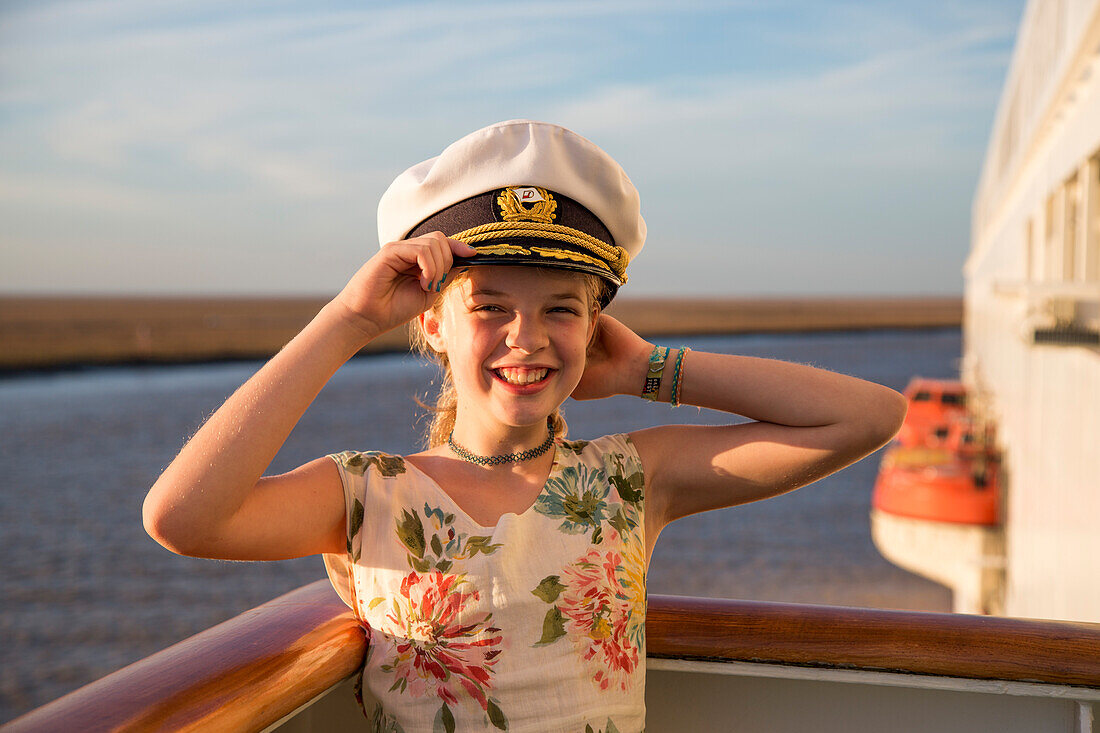 Junges Mädchen mit Kapitänsmütze auf der Brückennock von Kreuzfahrtschiff MS Deutschland (Reederei Peter Deilmann) bei Revierfahrt auf dem Fluss Guadalquivir, nahe Sevilla, Andalusien, Spanien, Europa [MR]