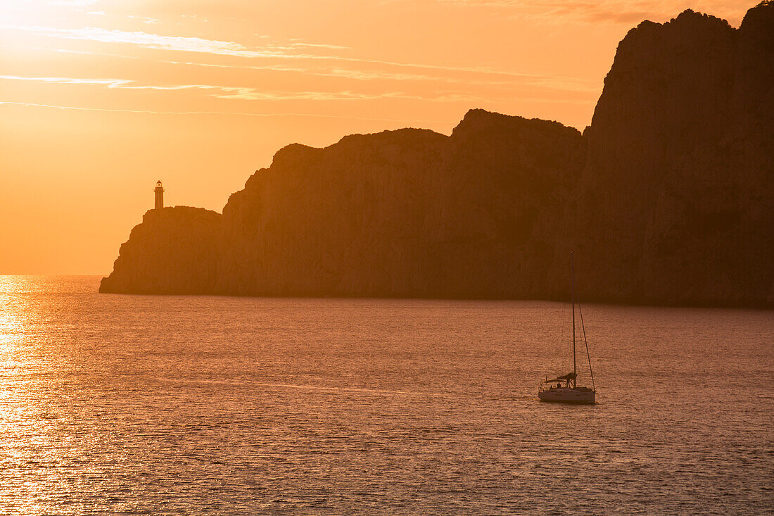 Silhouette of sailboat and Faro di Capri lighthouse at sunset, Isola di Capri, Campania, Italy