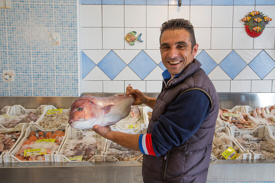 Fröhlicher Fischverkäufer in einem Fischladen, Porto Empedocle, Sizilien, Italien, Europa