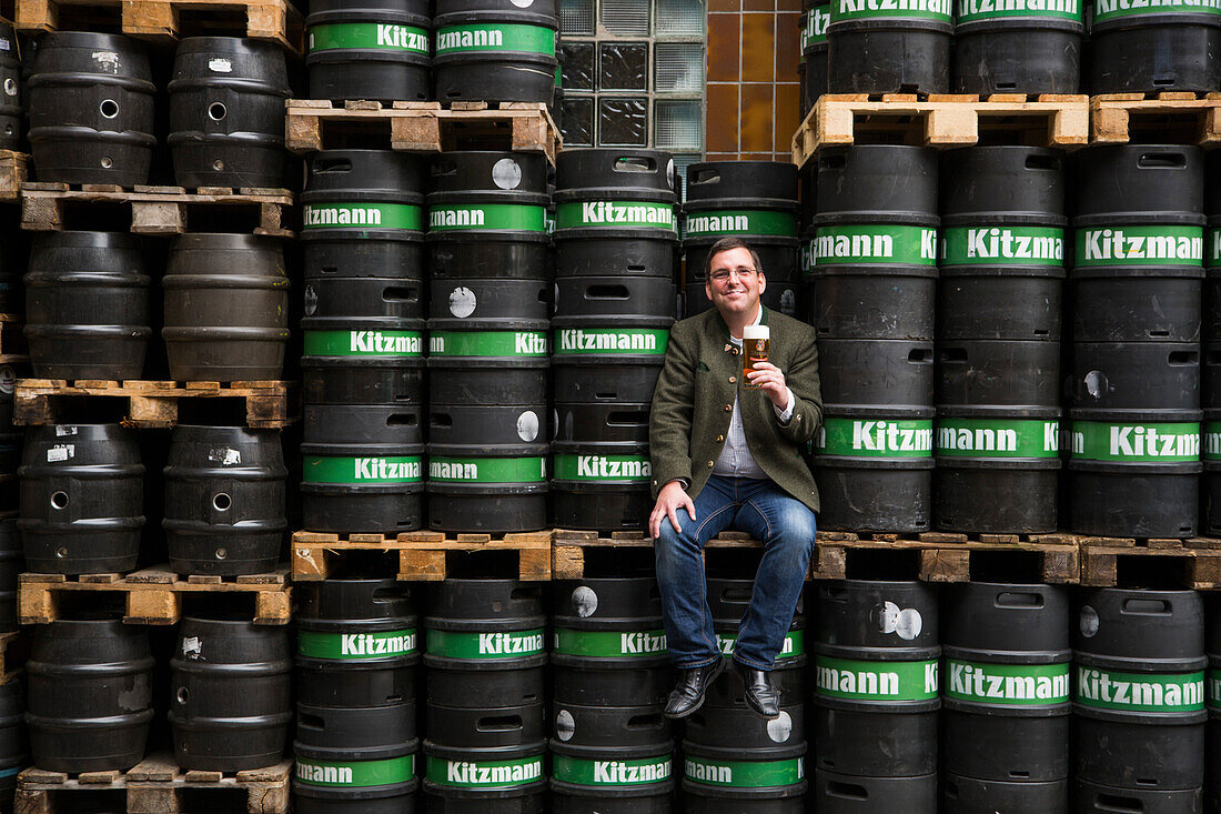 Brewmaster Benjamin Kloos sits among beer kegs at Kitzmann Bräu brewery, Erlangen, Franconia, Bavaria, Germany
