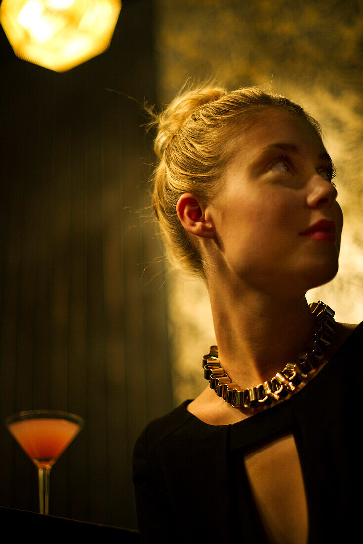 Woman sitting alone at night club bar looking away expectantly