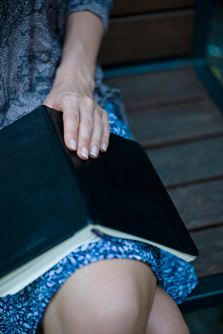 Woman sitting with open book on lap, cropped