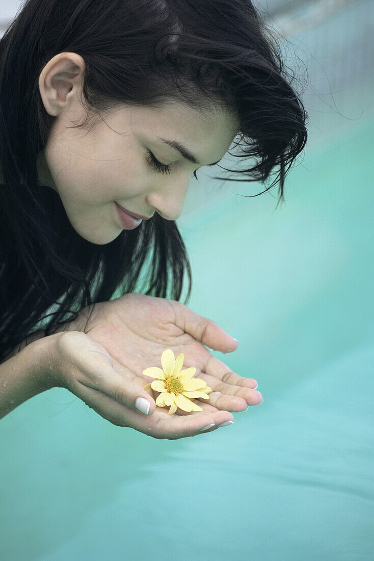 Young woman holding flower cupped in hands
