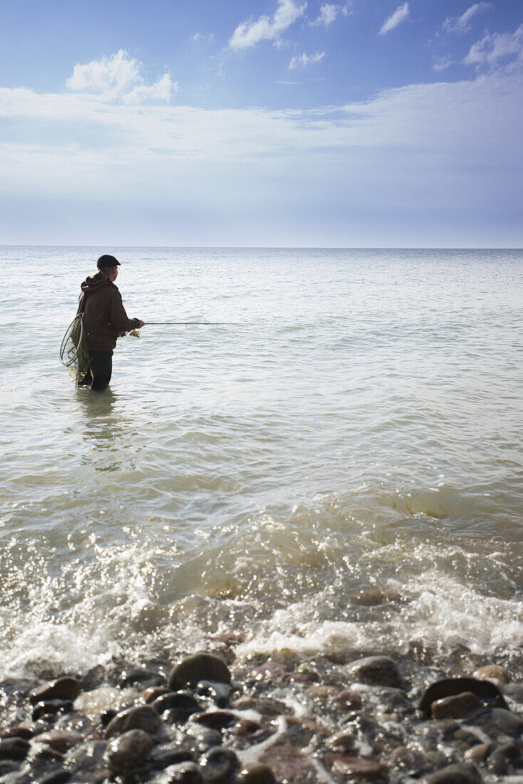 Angler steht in der Ostsee am Hohen Ufer im Nationalpark Vorpommersche Boddenlandschaft, Ahrenshoop, Fischland-Darß-Zingst, Mecklenburg Vorpommern, Deutschland