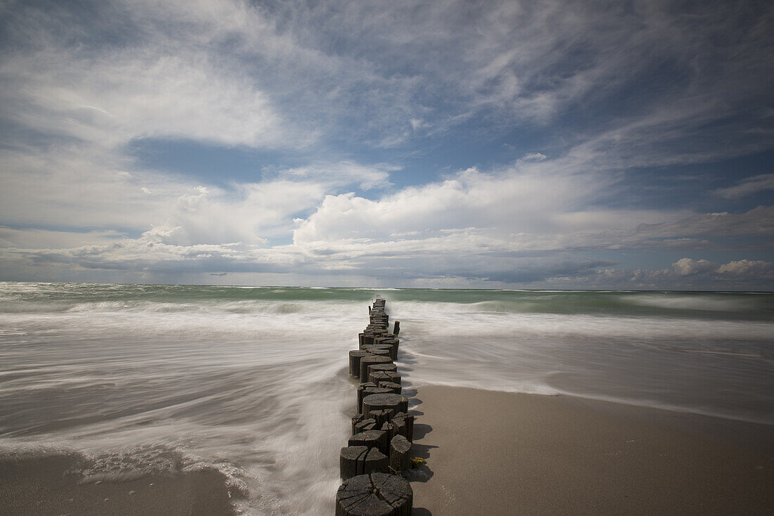 Long exposure of a cloudy sky and the Baltic Sea with groynes in the Western Pomerania Lagoon Area National Park, Ahrenshoop, Fischland-Darss-Zingst, Mecklenburg-Western Pomerania, Germany