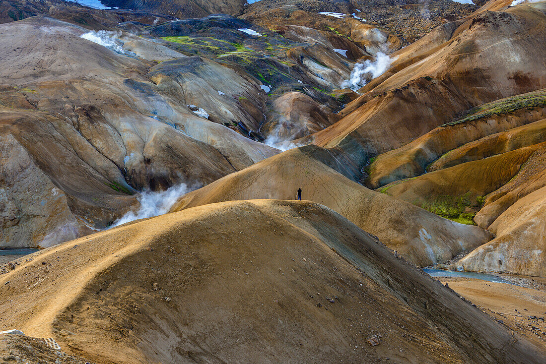 Hiker in Hveradalir, steam is rising out of colorful rhyolith mountains, volcanoe mountains Kerlingarfjoll, Highlands, South Iceland, Iceland, Europe