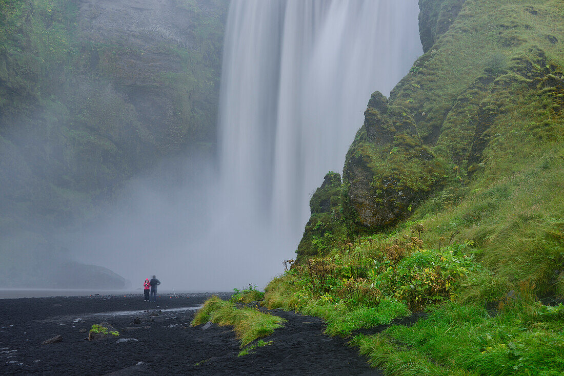 Junges Paar am Wasserfall Skógafoss nahe Skógar unterhalb des Eyjafjallajökull, Südisland, Island, Europa