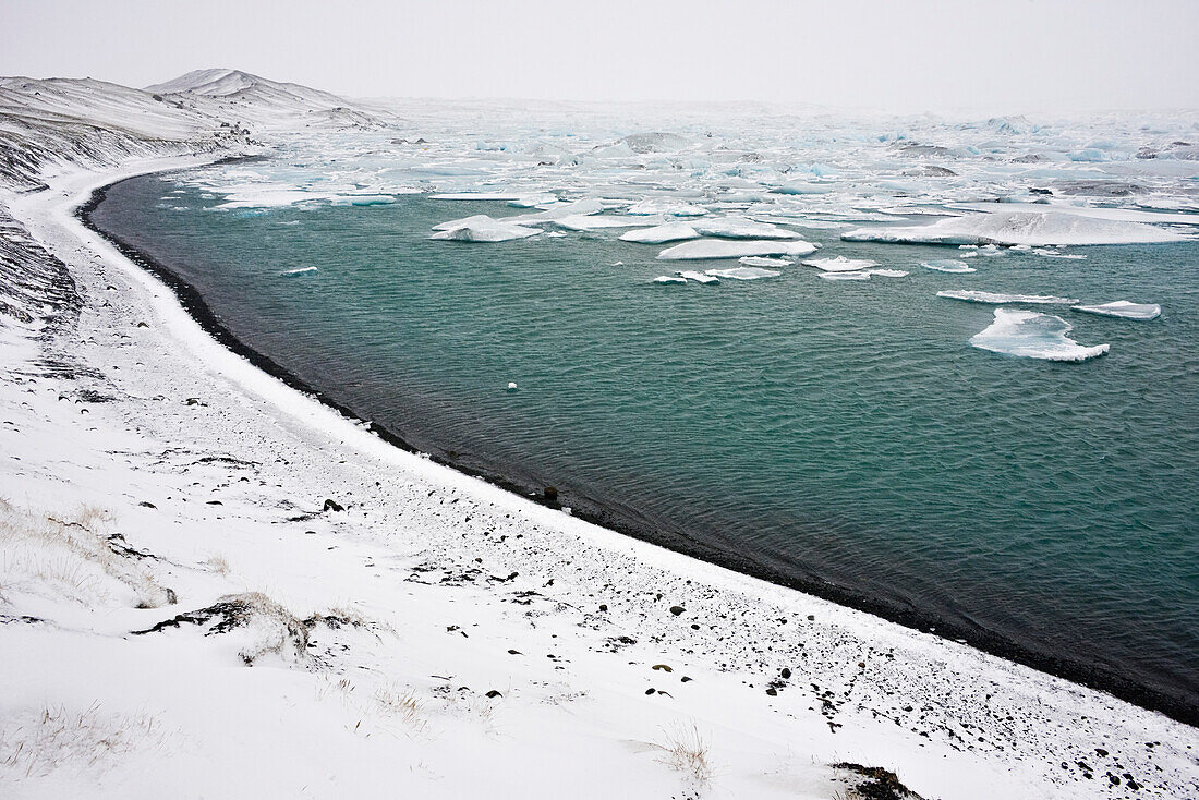 glacial lake Jokulsarlon with icebergs and snowy shore at Vatnajokull,  Breidamerkursandur between Skaftafell National Park und Hofn, East Iceland, Iceland, Europe