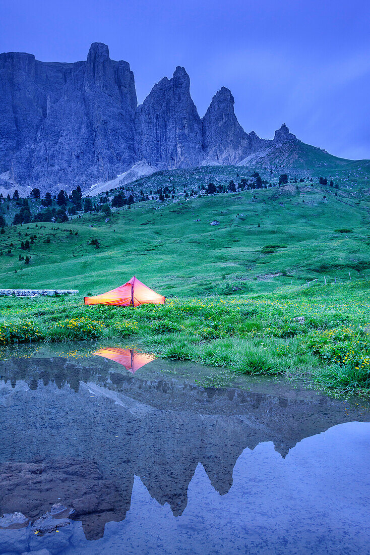 Illuminated tent and Sella range reflecting in mountain lake, Sella range, UNESCO world heritage Dolomites, Dolomites, Trentino, Italy