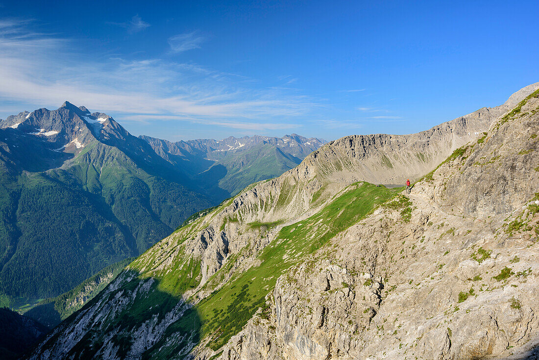 Woman ascending over rock ledge, Hoher Riffler in background, Lechtal Alps, Tyrol, Austria