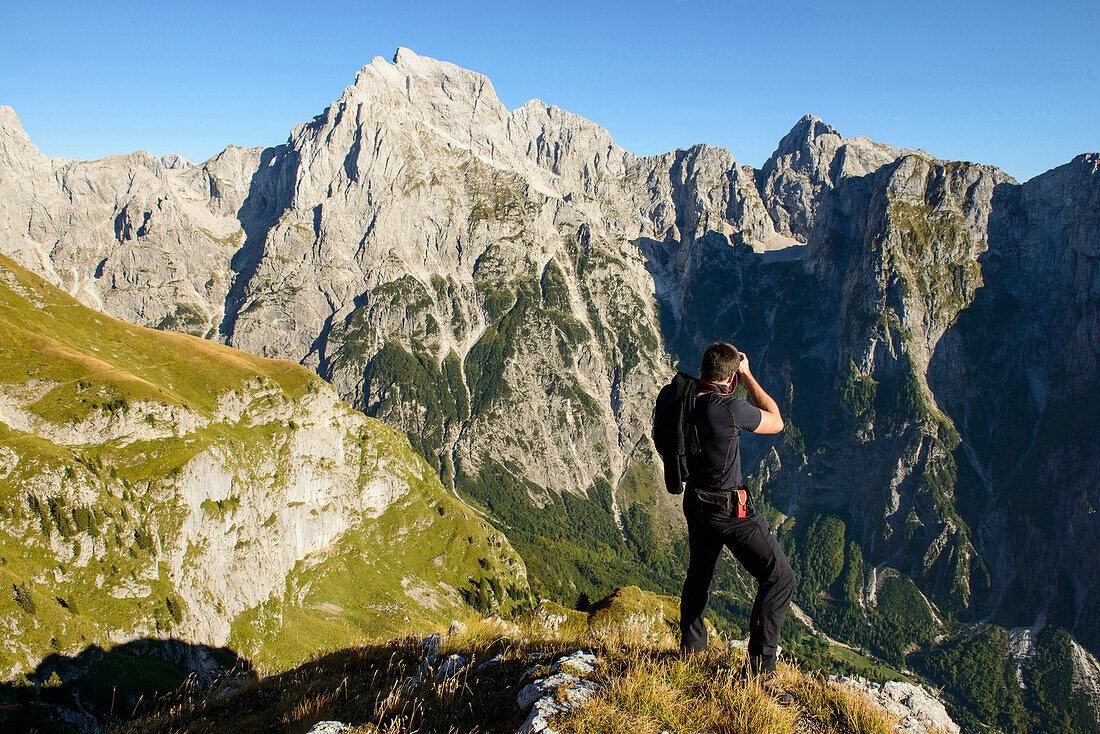 Hiker photographing craggy mountains, Mangart, Bovsko, Slovenia, Mangart, Bovsko, Slovenia