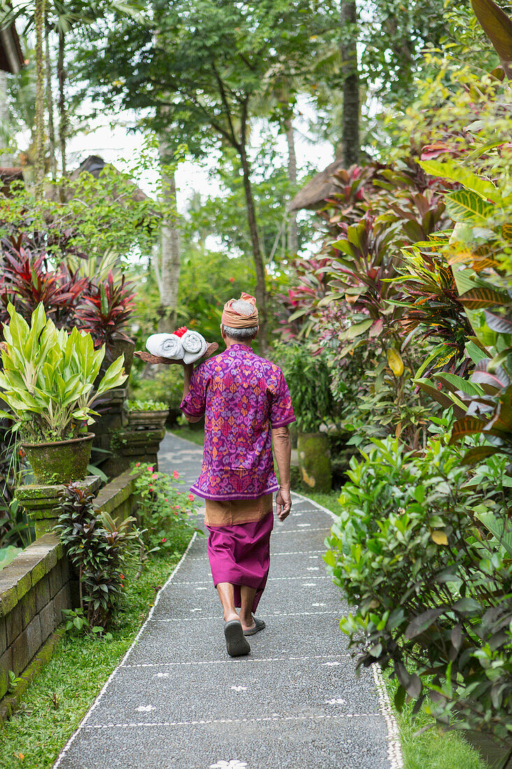 Balinese worker walking along path, Ubud, Bali, Indonesia