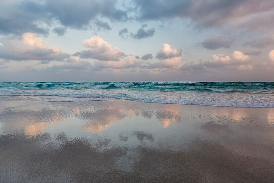 Clouds and sky reflected in still beach surf at sunrise, Qalansyia, Socotra, Yemen
