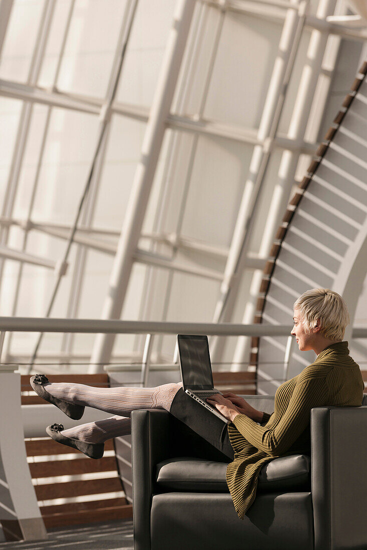 Caucasian businesswoman using laptop in lobby, Virginia Beach, VA, USA