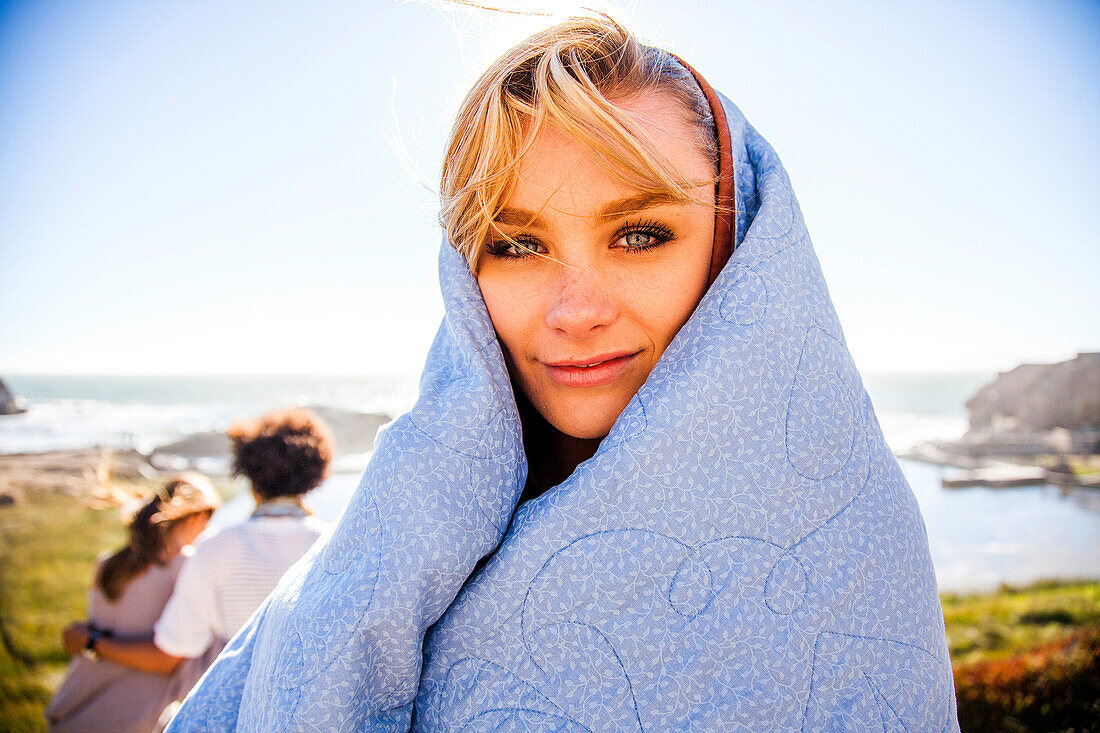 Woman wrapped in blanket on rural hillside, Oakland, California, United States
