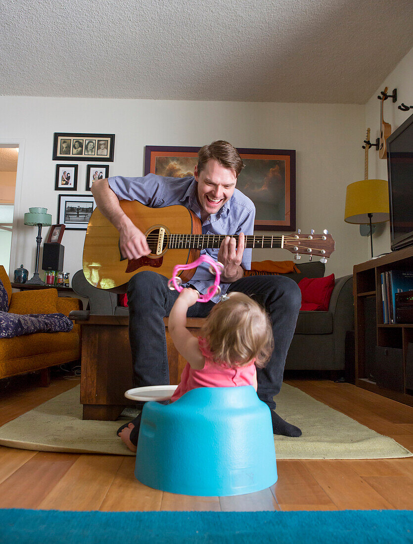 Caucasian father playing guitar for daughter, Los Angeles, California, USA