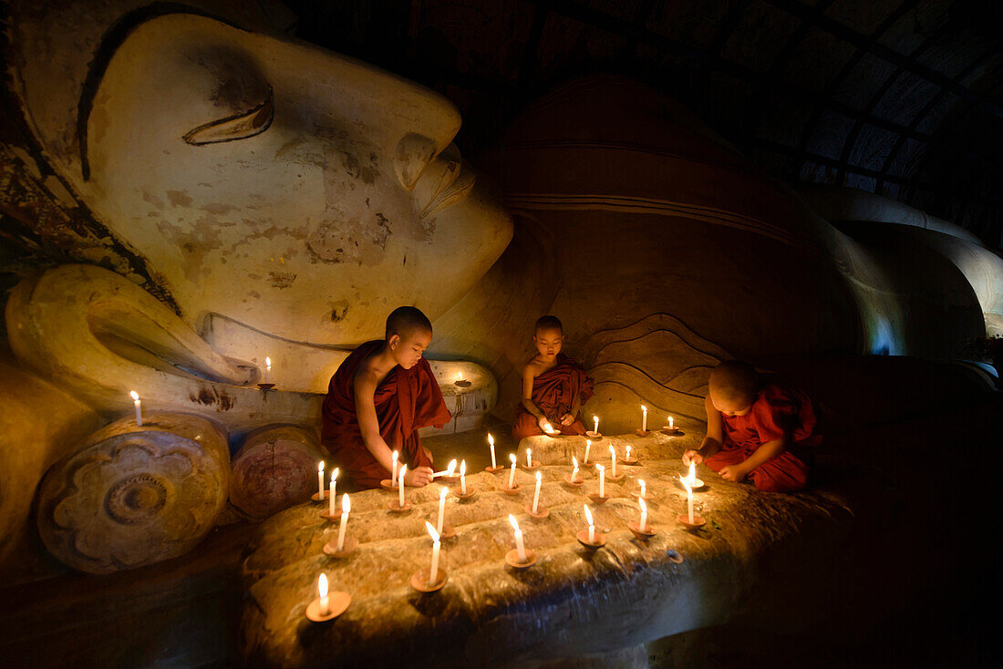 Asian monks lighting candles in temple, Bagan, Mandalay, Myanmar
